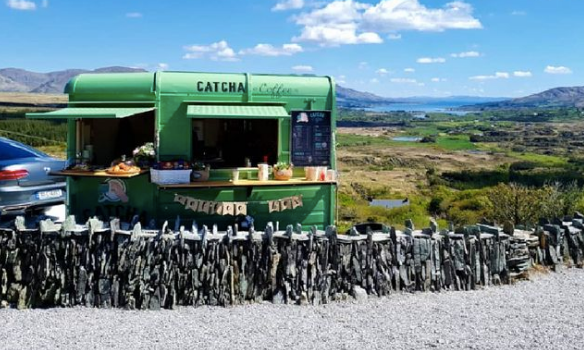 green coffee trailer with blue skies and countryside views in the background