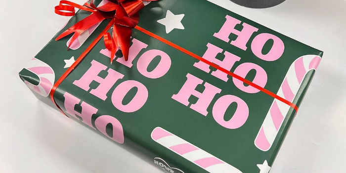 christmas present wrapped in green paper with the words "Ho Ho Ho" on it in pink