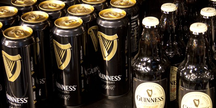 close up of multiple cans and bottles of guinness, positioned facing forward on a shelf