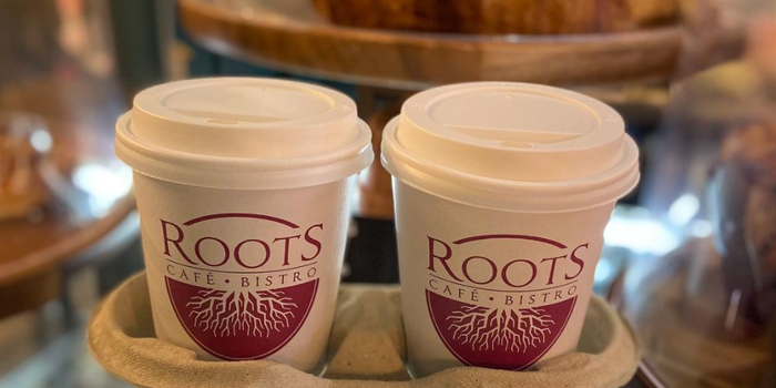 two takeaway coffee cups in a tray with the Roots logo