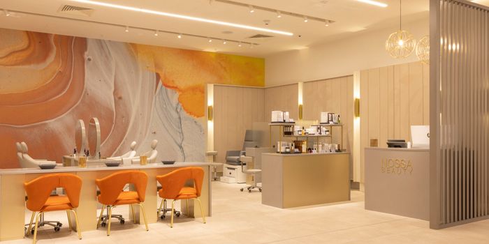 Beauty Lounge at Brown Thomas in Dundrum with an orange, blue and beige mural on the wall and selection of salon chairs