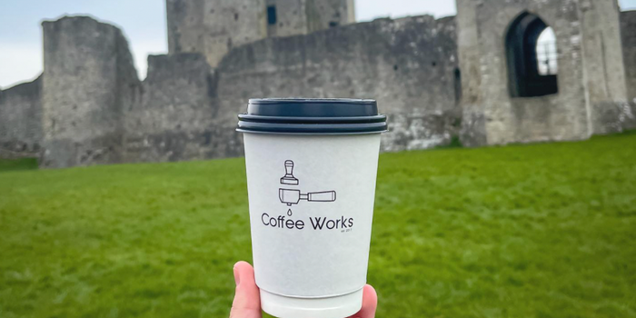 Coffee Works cup being held up outside Trim Castle