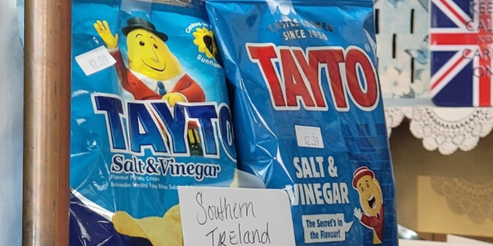two packets of salt and vinegar tayto, one with northern packaging, one with southern