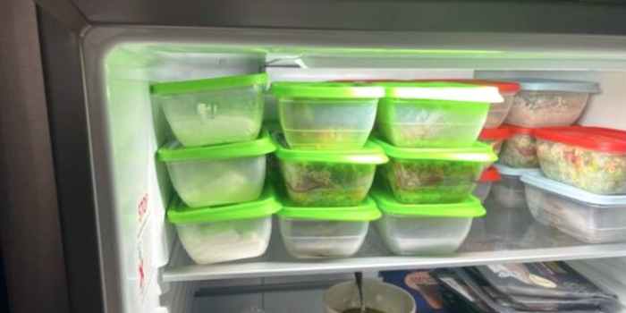 inside of a fridge showing multiple lunchboxes stacked on top of each other