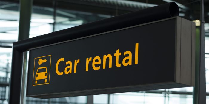 sign in an airport that reads "car rental" with an icon of a car and key