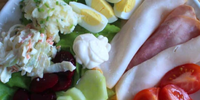 salad on a plate with hard boiled eggs, spring onion, lettuce, tomatoes, ham. beetroot and grated cheese