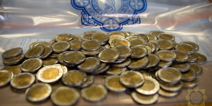 a pile of fake €2 coins on top of a gardai evidence plastic bag