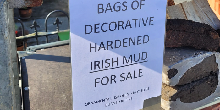 sign at a petrol station which reads "bags of decorative hardened Irish mud for sale"