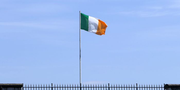 Irish flag on a pole with blue sky in the background