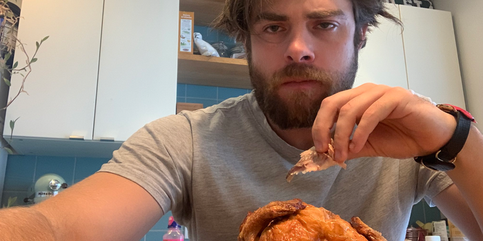 man taking a selfie while eating a rotisserie chicken