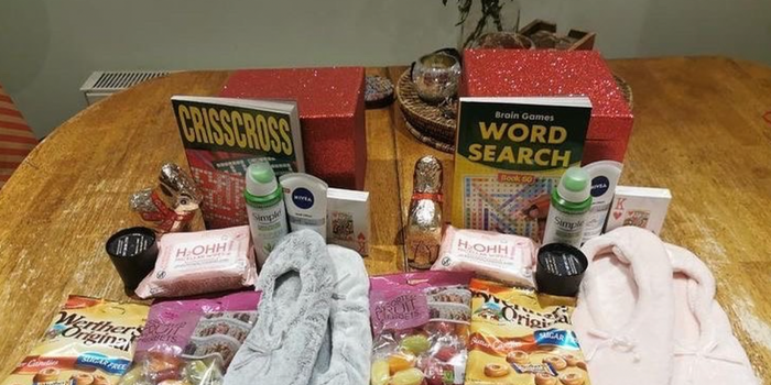crossword books, cards, slippers and bags of sweets being put together into a christmas package