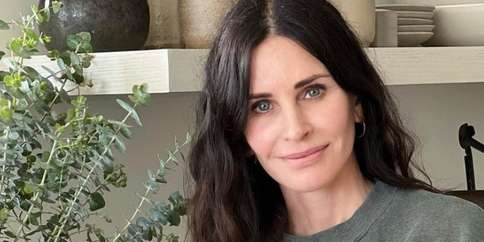 courteney cox looking at camera, wearing a green jumper