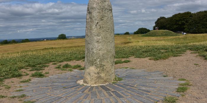 the Hill of Tara standing stone, with fields and blue sky in the background