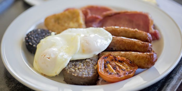 fry up breakfast on a plate with sausages, egg and pudding